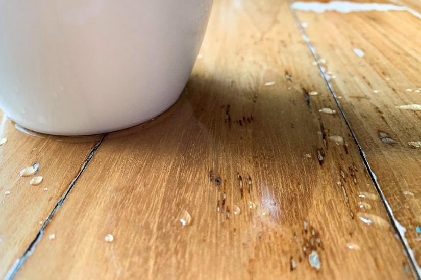 Water spilled on wooden surface from cup. Maintain wood furniture: cleaning water stains.