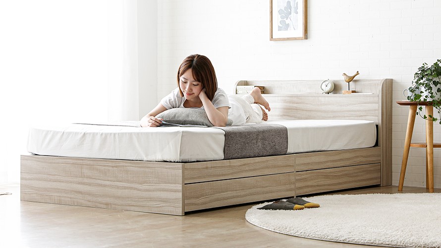 A lady enjoying the support from the Aube Storage Bed Frame with attractive natural grain.