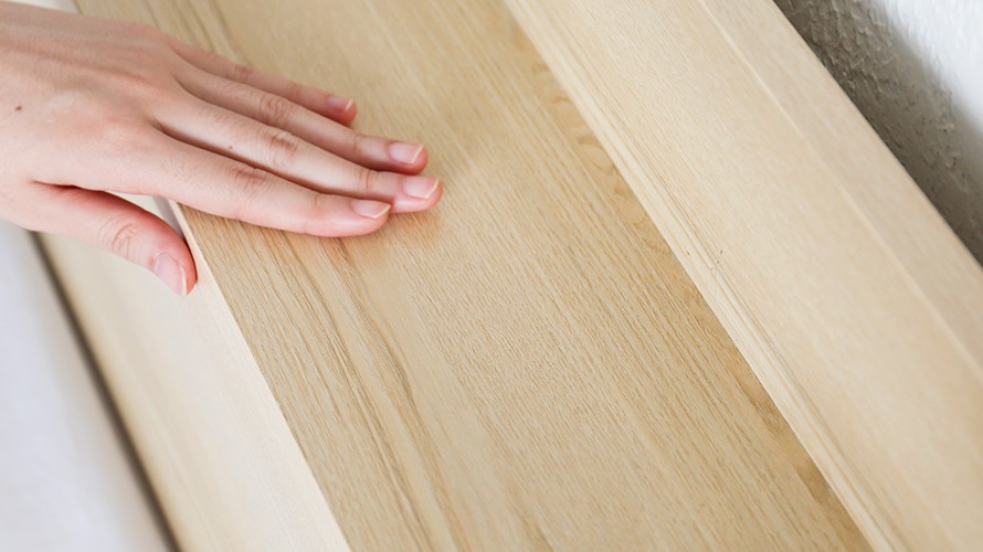 Hand touching the surface of the Aube Wooden Drawer Bed Frame. High-quality MDF wood is smooth to the touch and very strong.